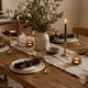 Rustic Modern Tablescape with gold cutlery, ceramic dinner plates, handcrafted candle holders, and natural fabric table textiles